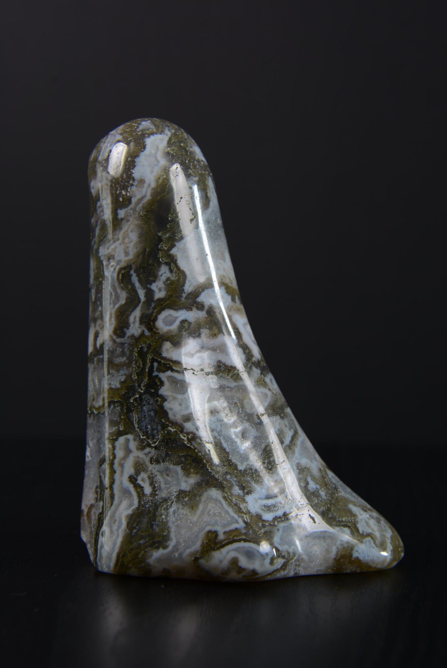 Profile angle of a polished ghost ornament, capturing the exquisite contours and the intricate play of light on its natural gemstone surface, emphasizing the ghost's ethereal beauty and craftsmanship.